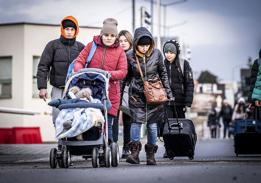 Ukrainerinnen am Grenzübergang zu Polen im März 2022, im Zentrum eine Frau mit Kinderwagen.