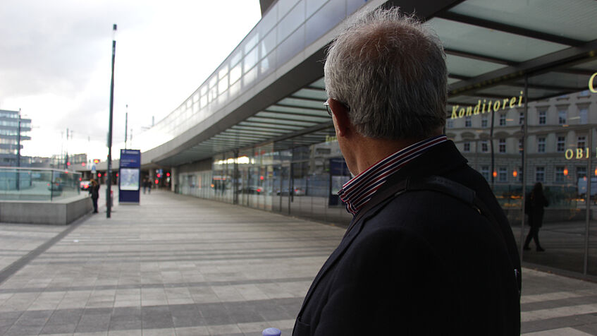 Ein Mann steht mit dem Rücken zur Kamera vor der hinteren Fassade des Hauptbahnhofes