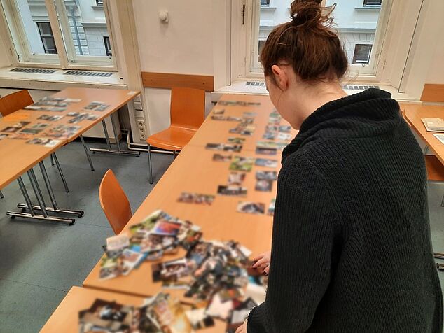Eine Projektmitarbeiterin beugt sich über einen Tisch mit vielen Bildern