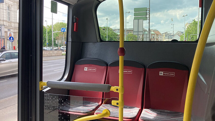 Foto vom hinteren Teil eines Busses der Wiener Linien, der die letzte Sitzreihe und die Umgebung in der Nähe der Bustür zeigt.