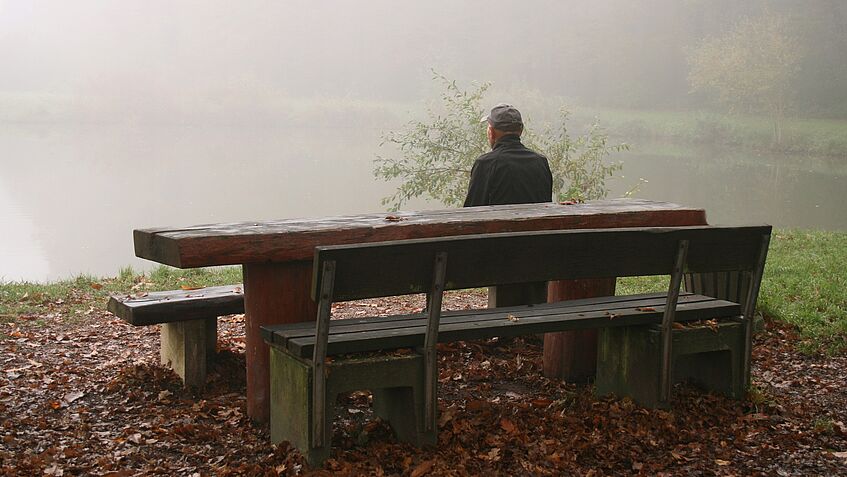 Mensch auf Parkbank bei grauem Wetter