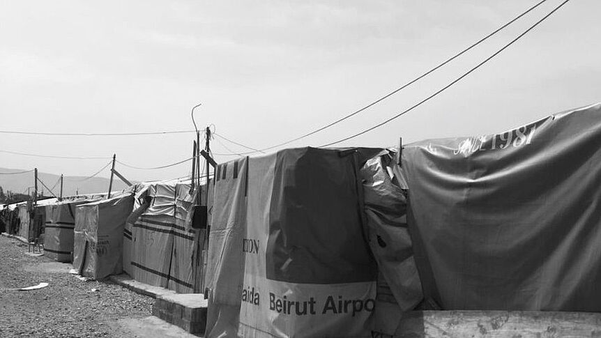 Schwarzweißbild ein Reihe von Zelten die sich im Bildhintergrund verliert. Eine der Planen trägt die Aufschrift 'Beirut Airport'