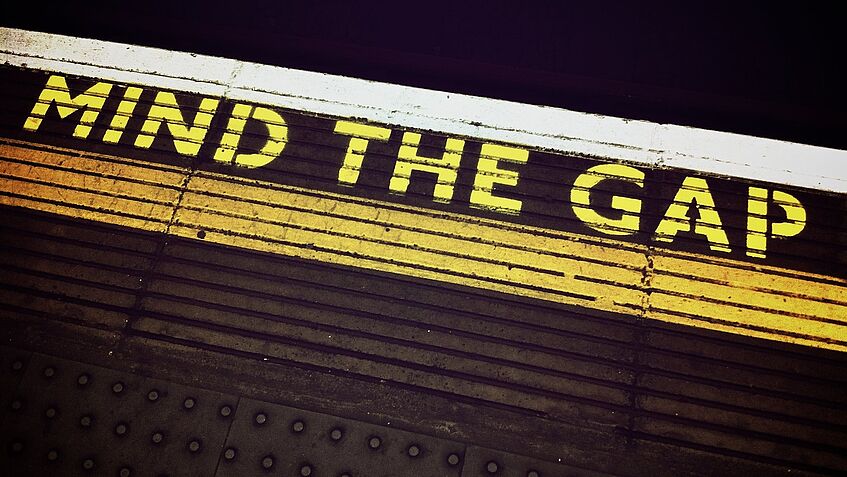 Bahnsteig in London, Gelber Schriftzug auf schwarzem Boden 'MIND THE GAP'
