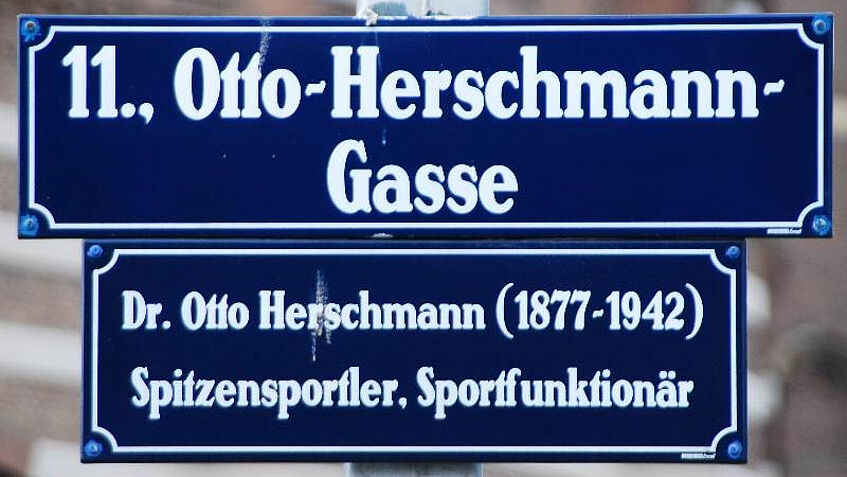 Straßenschild der Otto-Herschmann Gasse mit Zusatztafel: Dr. Otto Herschmann 1877-1942, Spitzensportler, Sportfunktionär