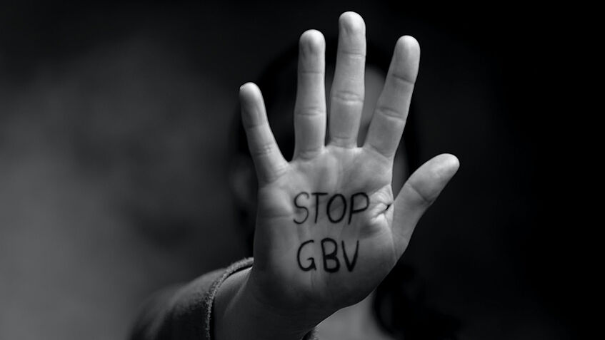 Schwarz-weiß-Aufnahme einer in die Kamera gestreckten flachen Hand, auf der Handfläche steht 'Stop GBV''