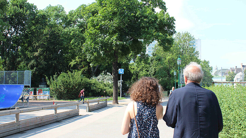 Blick auf den Rücken zweier Personen, die in einem Park spazieren