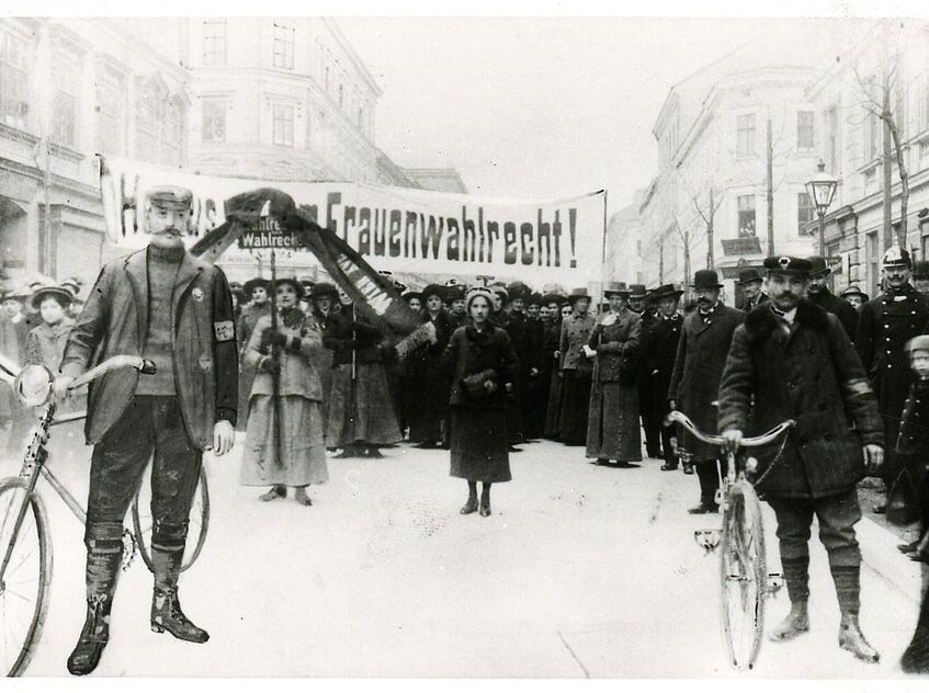 Demonstrationszug 1913 mit Banner, auf dem Frauenwahlrecht zu lesen ist